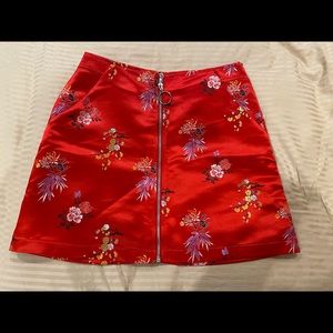 Short red satin skirt with flower detail embroidery.